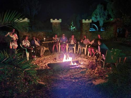 a group of people sitting around a fire at night at GKAT Resort in Mbarara