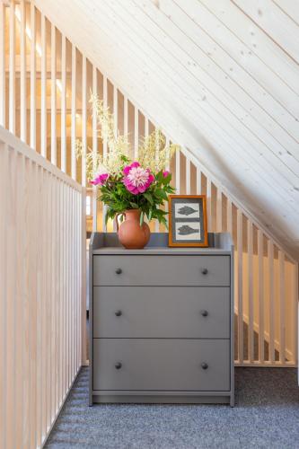 a dresser with a vase of flowers on top of it at B2 Apartments in Klaipėda