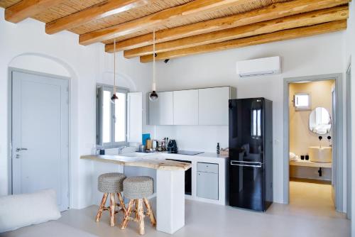 eine Küche mit einem schwarzen Kühlschrank und 2 Barhockern in der Unterkunft Mystic Villas Koufonisi in Koufonisia