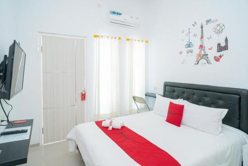 1 dormitorio con 1 cama con manta roja y blanca en RedDoorz Syariah At Winong Nganjuk, en Nganjuk