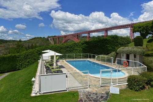 a swimming pool with a bridge in the background at Logis Hôtel Beau Site in Loubaresse