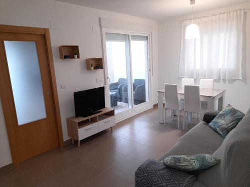 uma sala de estar com um sofá, uma televisão e uma mesa em Blaumar em Piles