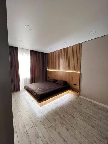 Un dormitorio con una cama y suelo de madera. en ЖК на Исы Байзакова, en Pavlodar