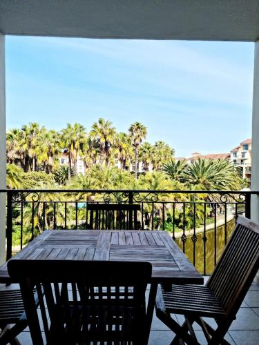 a wooden table and chairs on a balcony with palm trees at Island Club by Smart City Stays in Cape Town