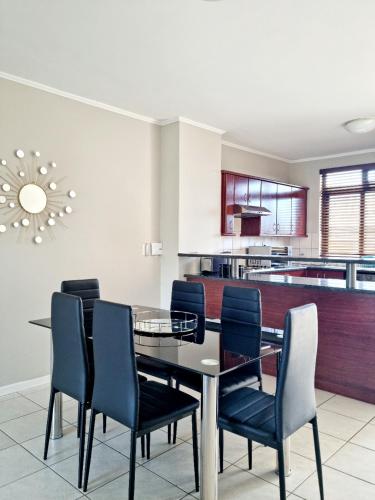 a dining room with a glass table and blue chairs at Island Club by Smart City Stays in Cape Town