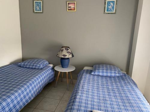 une chambre avec deux lits et une lampe sur une table dans l'établissement Appartement 2 chambres et cuisine VIERVILLE-SUR-MER,plage du Débarquement, à Vierville-sur-Mer
