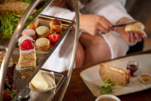 a woman sitting in a bed with a tray of food at Manor House Hotel in Bishop Auckland