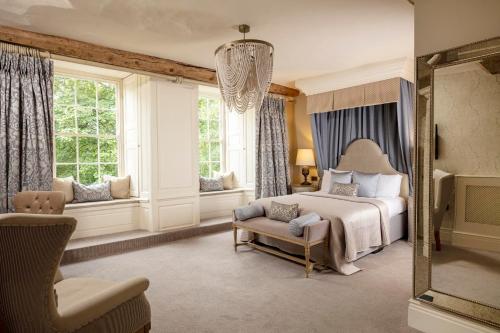 a bedroom with a bed and a chair and windows at Manor House Hotel in Bishop Auckland