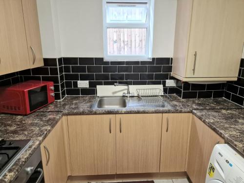 a kitchen with a sink and a microwave at Mile End Budget Guesthouse in London