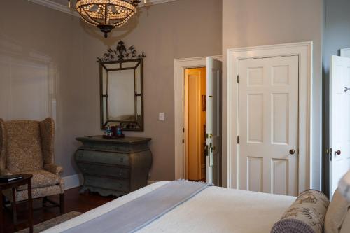a bedroom with a bed and a mirror and a chair at Eliza Thompson House, Historic Inns of Savannah Collection in Savannah