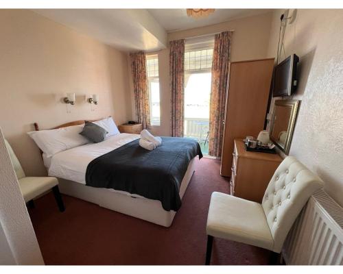 um quarto com uma cama, uma televisão e uma cadeira em Bonair Hotel em Paignton