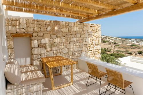 a patio with a table and chairs and a stone wall at Mystic Villas Koufonisi in Koufonisia