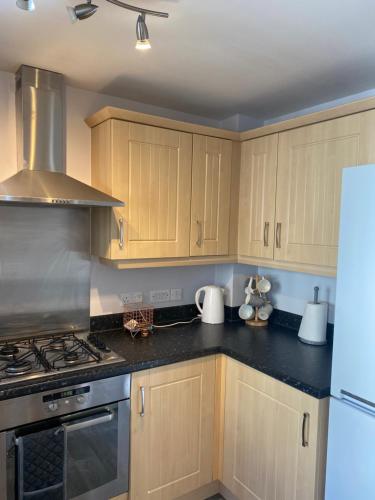 a kitchen with wooden cabinets and a stove top oven at Coventry City Centre townhouse with private parking in Coventry