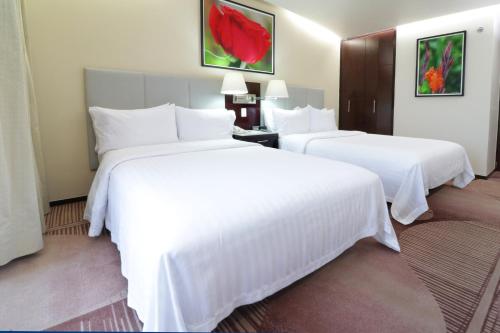 two beds in a hotel room with white sheets at Holiday Inn Hotel & Suites Mexico Medica Sur by IHG in Mexico City