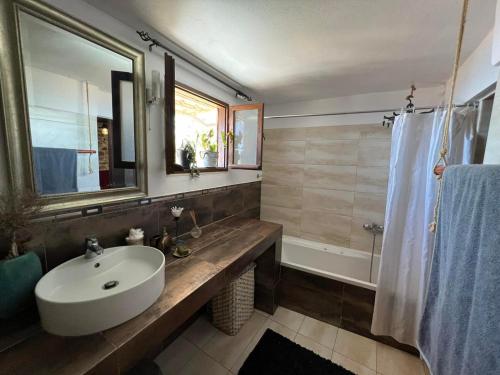 uma casa de banho com um lavatório, um espelho e uma banheira em Πετροχτιστο Αρχοντικό με υπεροχή θεα em Rodhiá