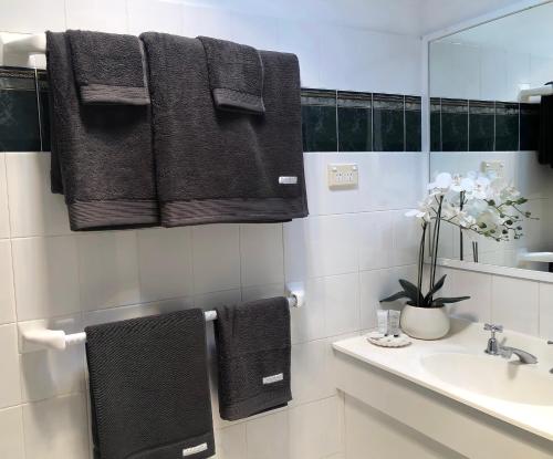uma casa de banho com toalhas pretas penduradas por cima de um lavatório em Black Range Lodge em Tumbarumba