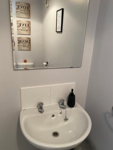 a white sink in a bathroom with a mirror at Coventry City Centre townhouse with private parking in Coventry