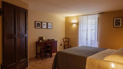 a bedroom with a bed and a desk and a window at Alloggio del Vicolo - Le Vecchie Vasche in Coppito