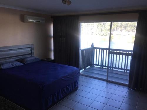 a bedroom with a blue bed and a balcony at Mzingazi Waterfront Richards Bay in Richards Bay