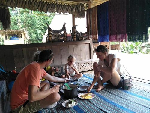 Arnolds Familly homestay في Bajawa: مجموعة من الناس جالسين على الأرض يأكلون الطعام
