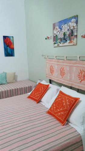 two beds with orange and white pillows in a room at 4 stagioni in Villasimius