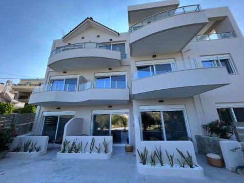 a white house with two balconies and two chairs at Aelia Apartments in Makry Gialos