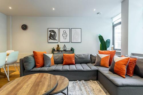 ロンドンにあるStunning Modern Apartment in the Heart of Holbornのリビングルーム(オレンジ色の枕とグレーのソファ付)