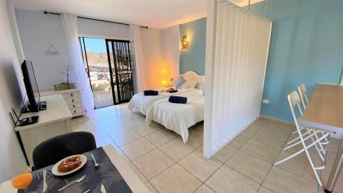 1 dormitorio con cama, mesa y TV en Blue Cristianos by W Tenerife, en Los Cristianos