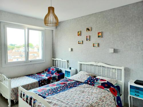 een slaapkamer met 2 bedden en een raam bij Appartement sur Port - 78m2 Balcon in Saint-Gilles-Croix-de-Vie
