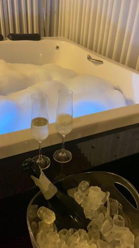 two glasses of wine next to a bath tub at FIKA Residence in Dois Irmãos