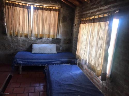 una piccola camera con un letto in una stanza con finestre di Pachamama cabañas en la montaña a Mina Clavero