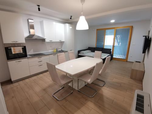 a kitchen and living room with a white table and chairs at PUBYLAND ROOMS & APARTMENTS in Rogatec