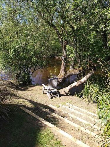 a bench sitting under a tree next to a river at lodge avec vue sur la rivière in Lannion