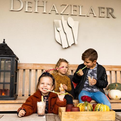 three children sitting on a bench eating food at Hof van Salland Hellendoorn in Hellendoorn
