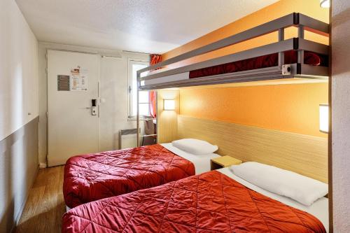 two beds in a hotel room with red sheets at Premiere Classe Beauvais in Beauvais