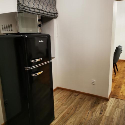 a black refrigerator with a microwave on top of it at Apartament Zielony in Włodawa
