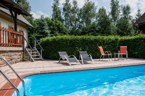 a pool with chairs and a table next to a house at Pension Herman in Rudník