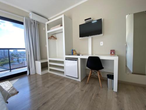 a room with a desk with a tv and a chair at Hayer Hotel in Erechim