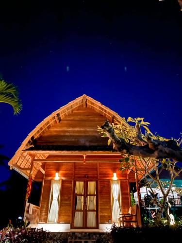 a wooden house with a thatched roof at night at Griyatama Bungalow in Nusa Penida