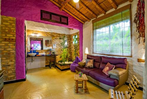 a living room with a purple couch and a kitchen at Hotel Campestre Solar De La Luna in Armenia