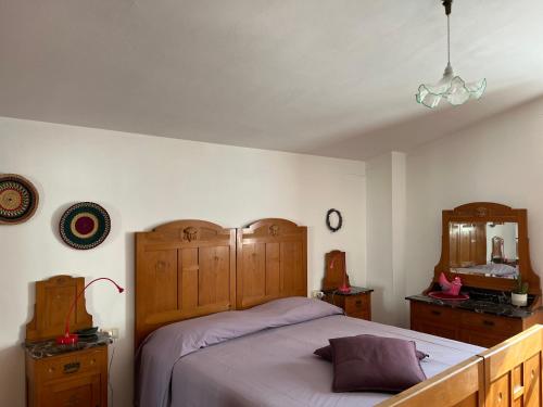 a bedroom with a bed with a wooden headboard and a mirror at La luna e i falò in Arezzo
