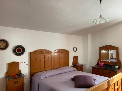 - une chambre avec un lit doté d'une tête de lit en bois et d'un miroir dans l'établissement La luna e i falò, à Arezzo