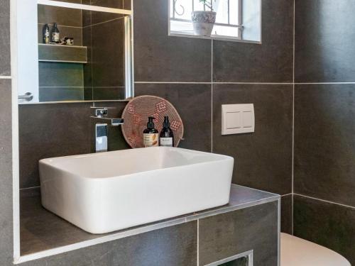 een badkamer met een witte wastafel en een spiegel bij Villa Palmera Load shedding FREE in Mosselbaai