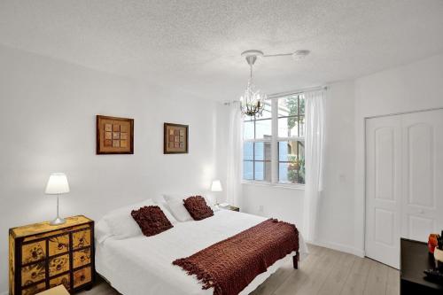 a white bedroom with a bed and a window at Yacht Club Newly renovated parking included in Aventura