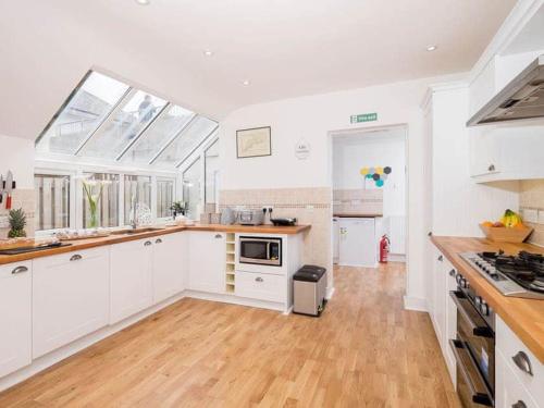 a large kitchen with white cabinets and a wooden floor at Glas Mordros in St Ives