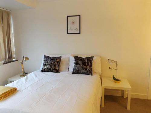 ein Schlafzimmer mit einem weißen Bett mit Kissen darauf in der Unterkunft Gainford House in Walsgrave on Sowe