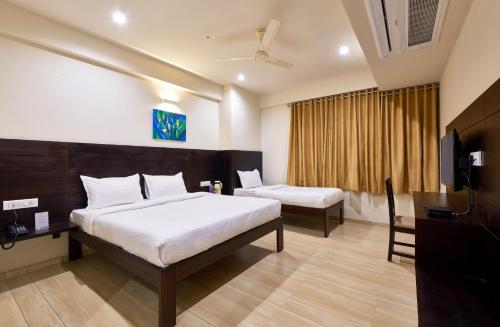a hotel room with two beds and a television at Hotel Tulsi-100 Feet From Ambabai Temple, Kolhapur in Kolhapur