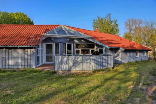 a small house with an orange roof on a field at Kranich Ferienhäuser mit Innenpool in Hohendorf