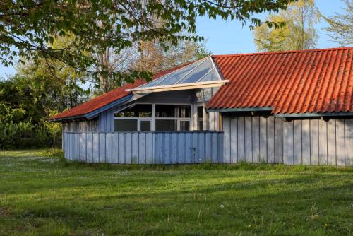 a house with a red roof and a green field at Kranich Ferienhäuser mit Innenpool in Hohendorf