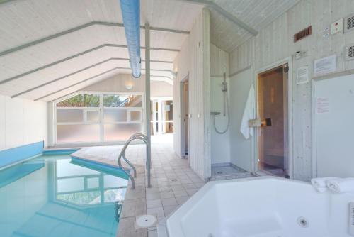 a bathroom with a swimming pool and a tub at Kranich Ferienhäuser mit Innenpool in Hohendorf